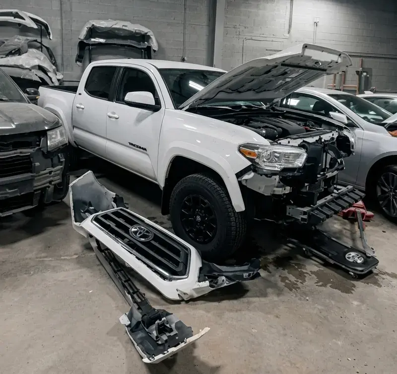 Technician repairing collision damage on a car bumper at Kairos Auto Center in Worcester, MA