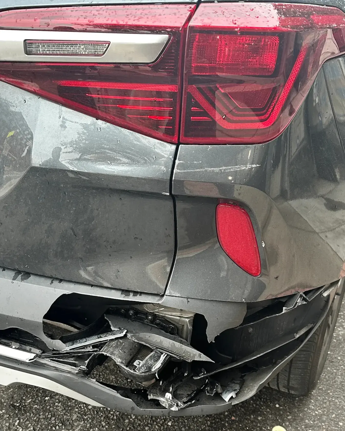Rear bumper and tail light crushed after a collision, before repair at Kairos Auto Center